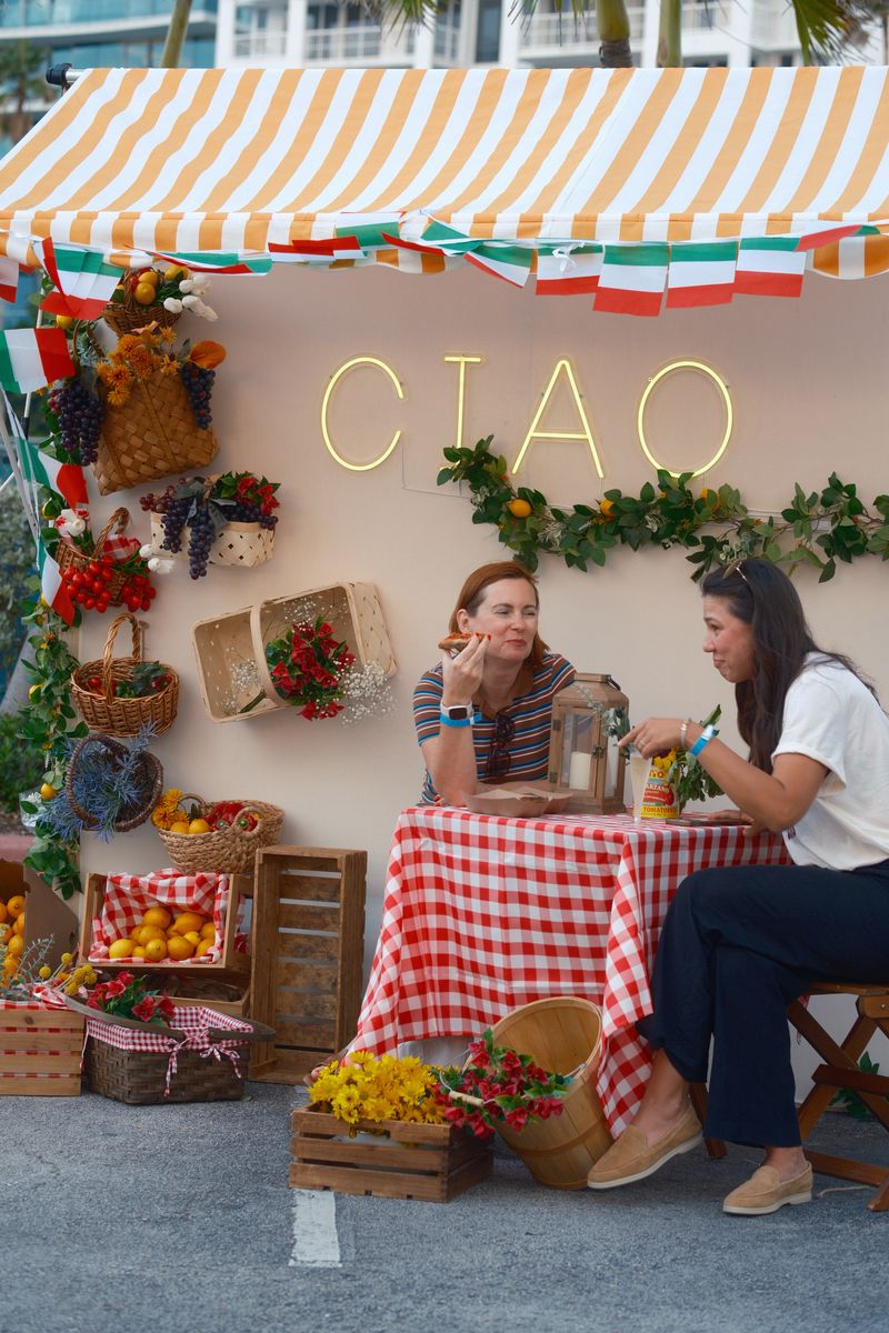 Guests at the market set with fruit crates and a neon Ciao sign