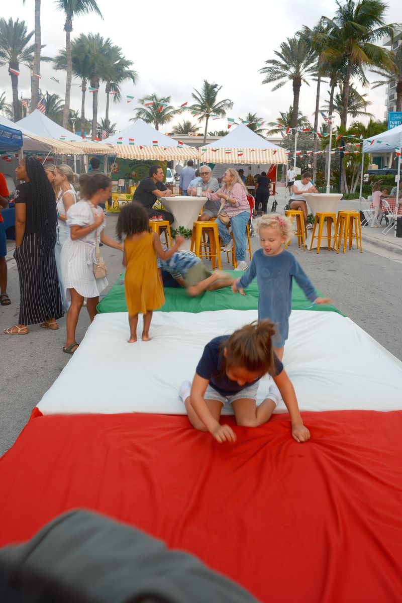 Children playing on a red, white and green installation on the street