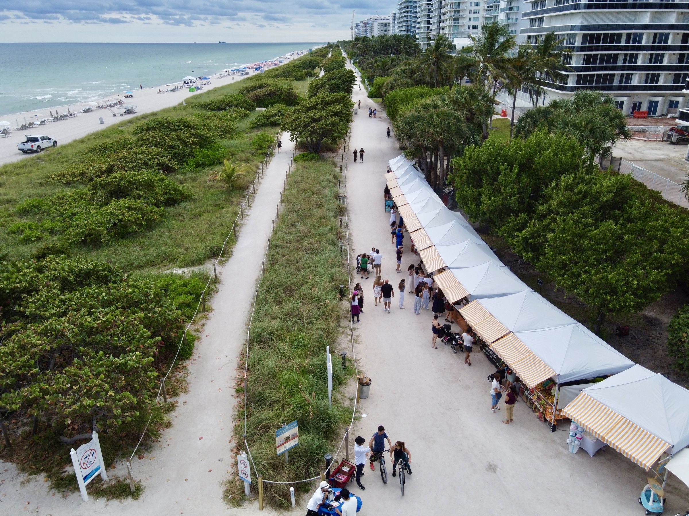 Aerial view of the market tents along the beach path in Surfside, with the ocean beside them