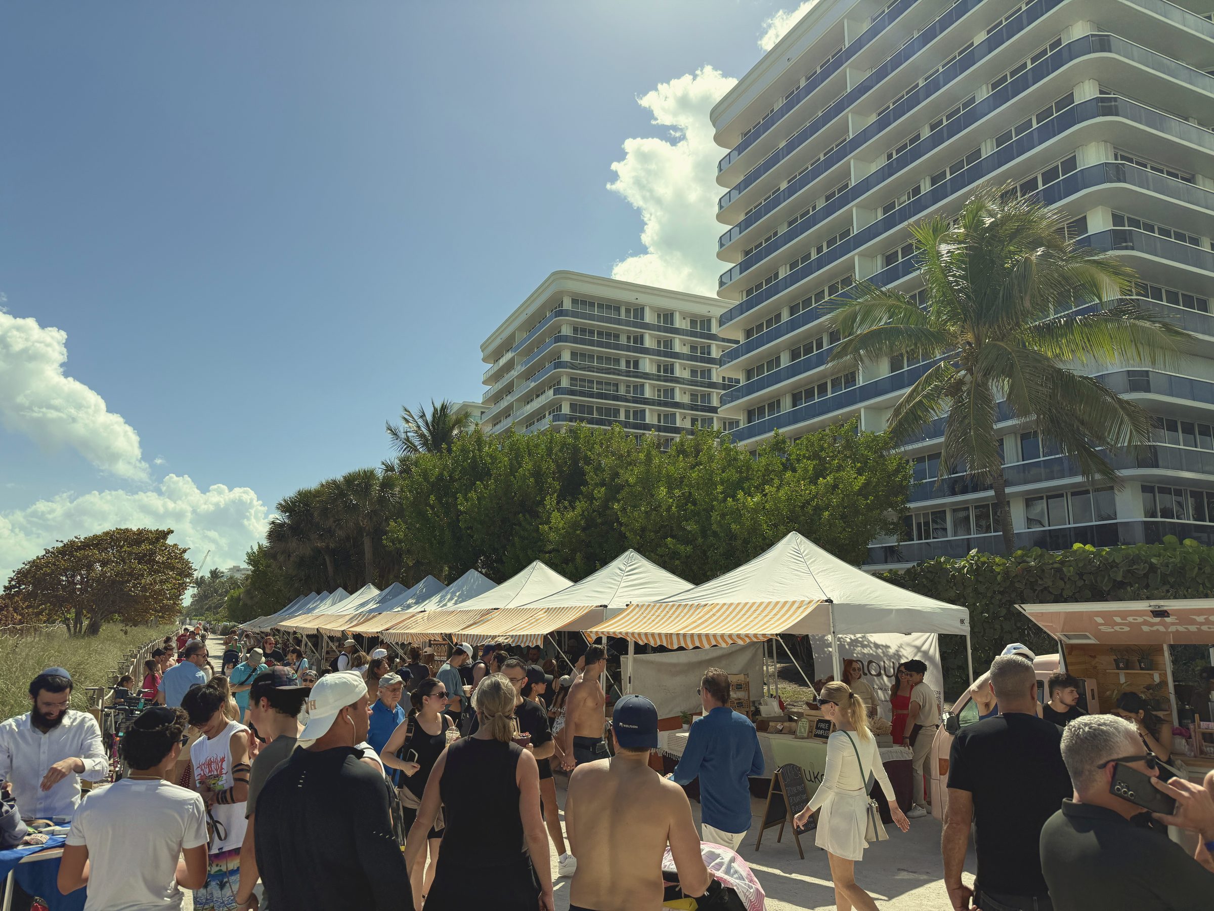 Crowds filling the path between the tent rows beneath Surfside's oceanfront buildings