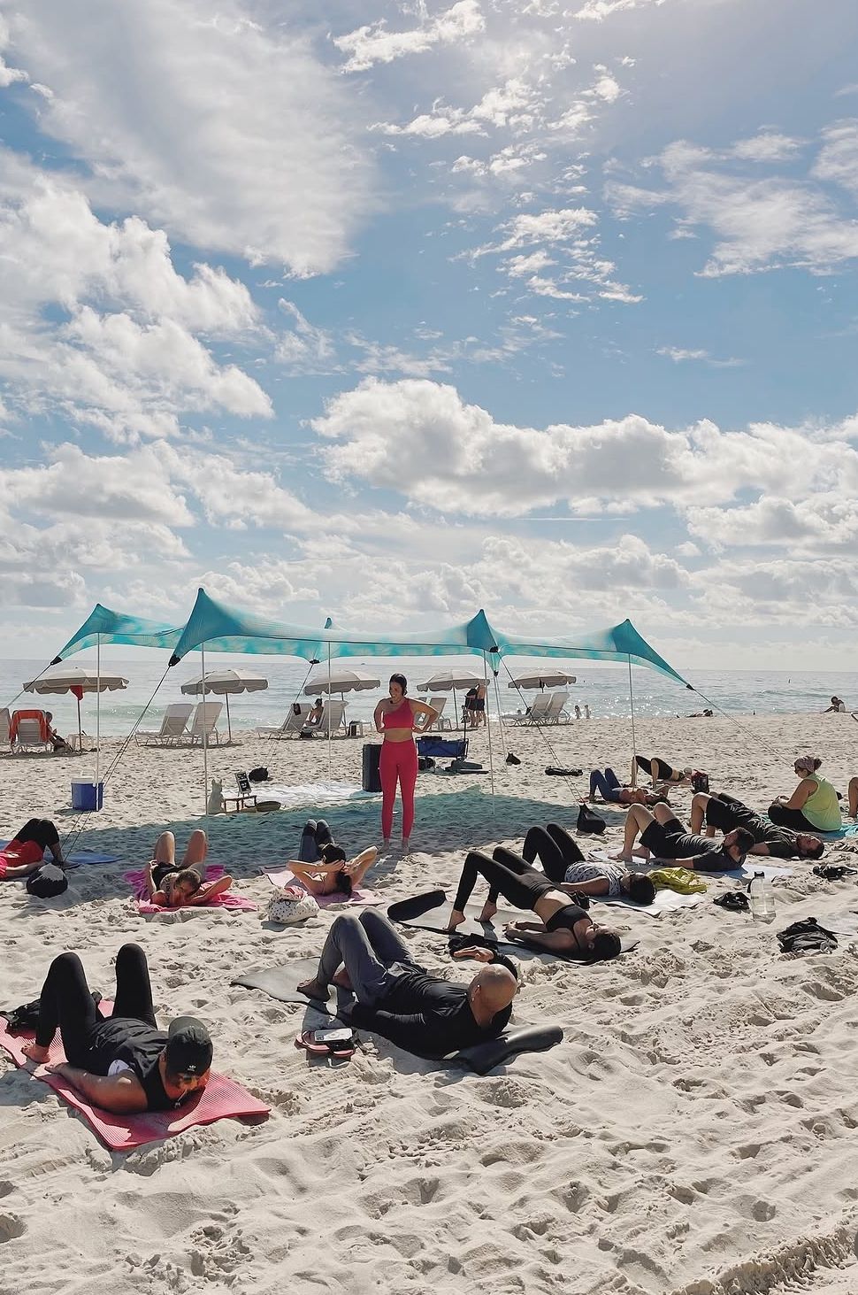 Beach Yoga on the sand under teal shade canopies