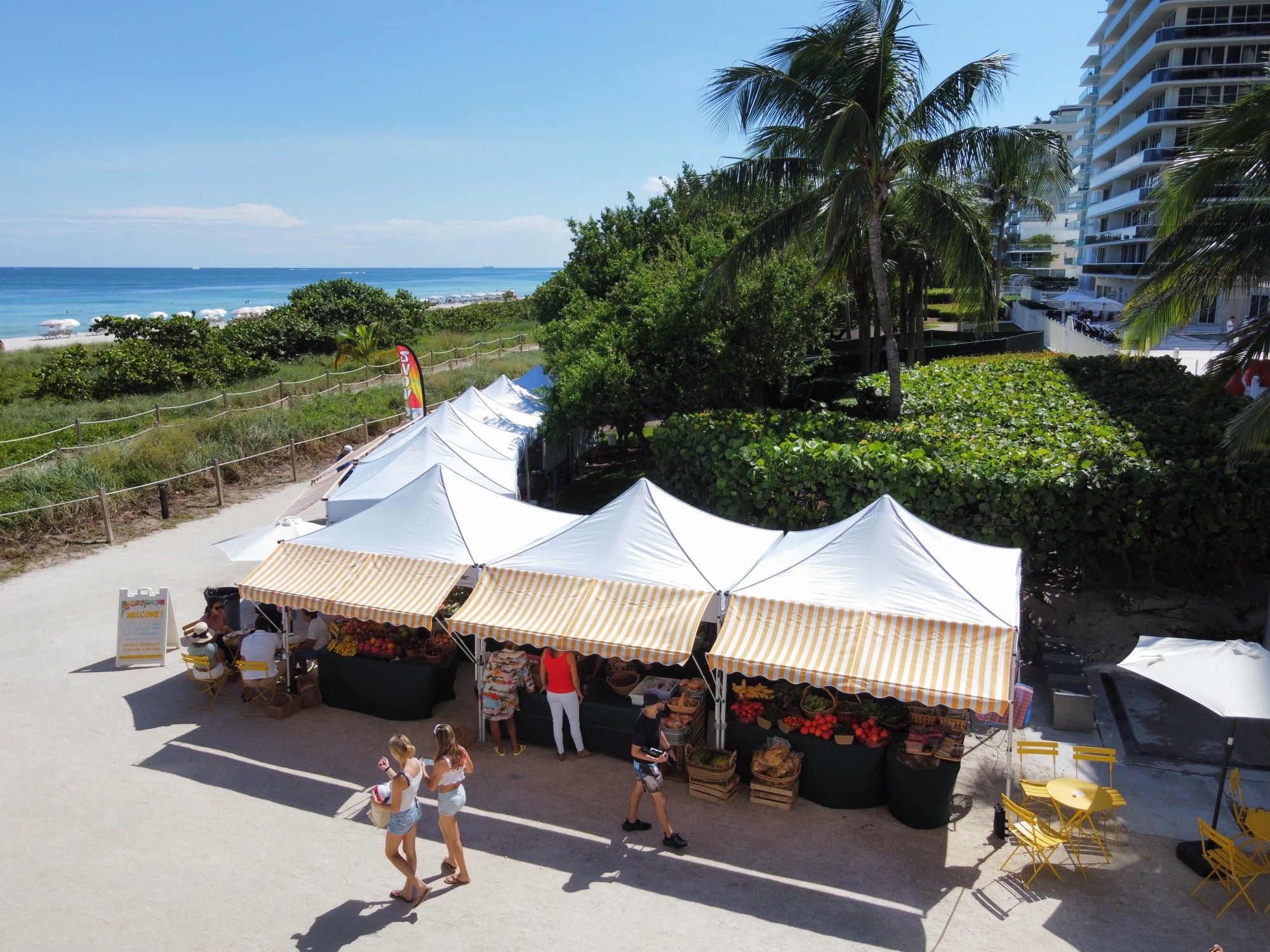 Aerial view of striped vendor tents between the dunes and the beach path